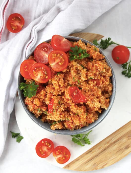 Tomato quinoa served in a bowl on a wooden board.
