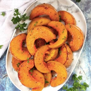 Roasted butterkin squash wedges served on a plate.