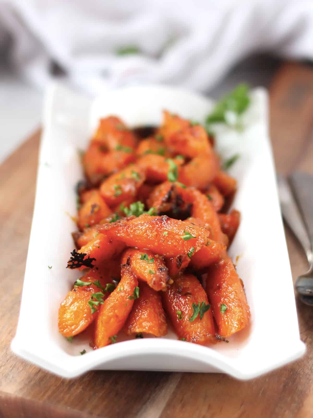 Maple mustard glazed carrots on a white serving plate.