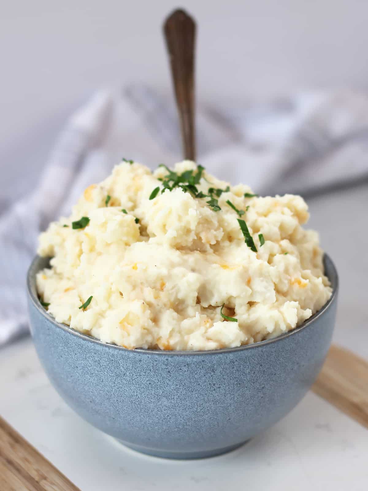Mashed potato with cheese and garlic in a blue bowl.