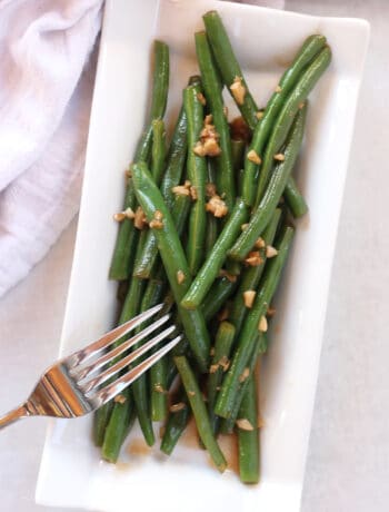Balsamic green beans served on a white oblong plate with a fork.