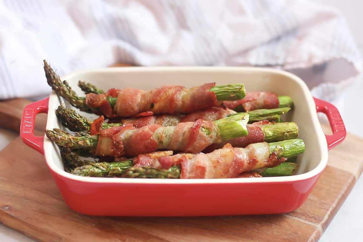 Bacon wrapped asparagus piled on top of each other in a serving dish.