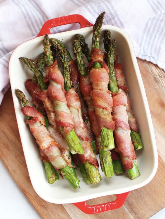 Bacon wrapped asparagus spears in a red and white serving dish.