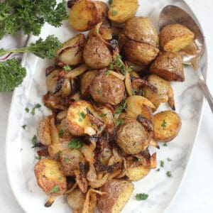 Air fryer potatoes and onions on a plate with a serving spoon.