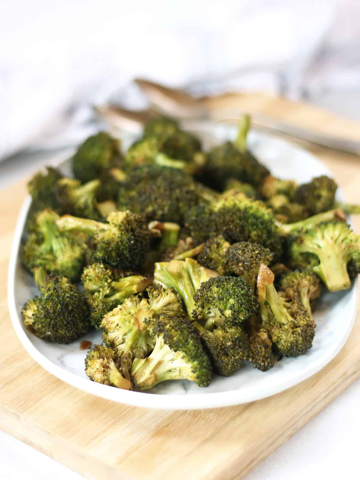 Balsamic broccoli served on a plate on a wooden chopping board.
