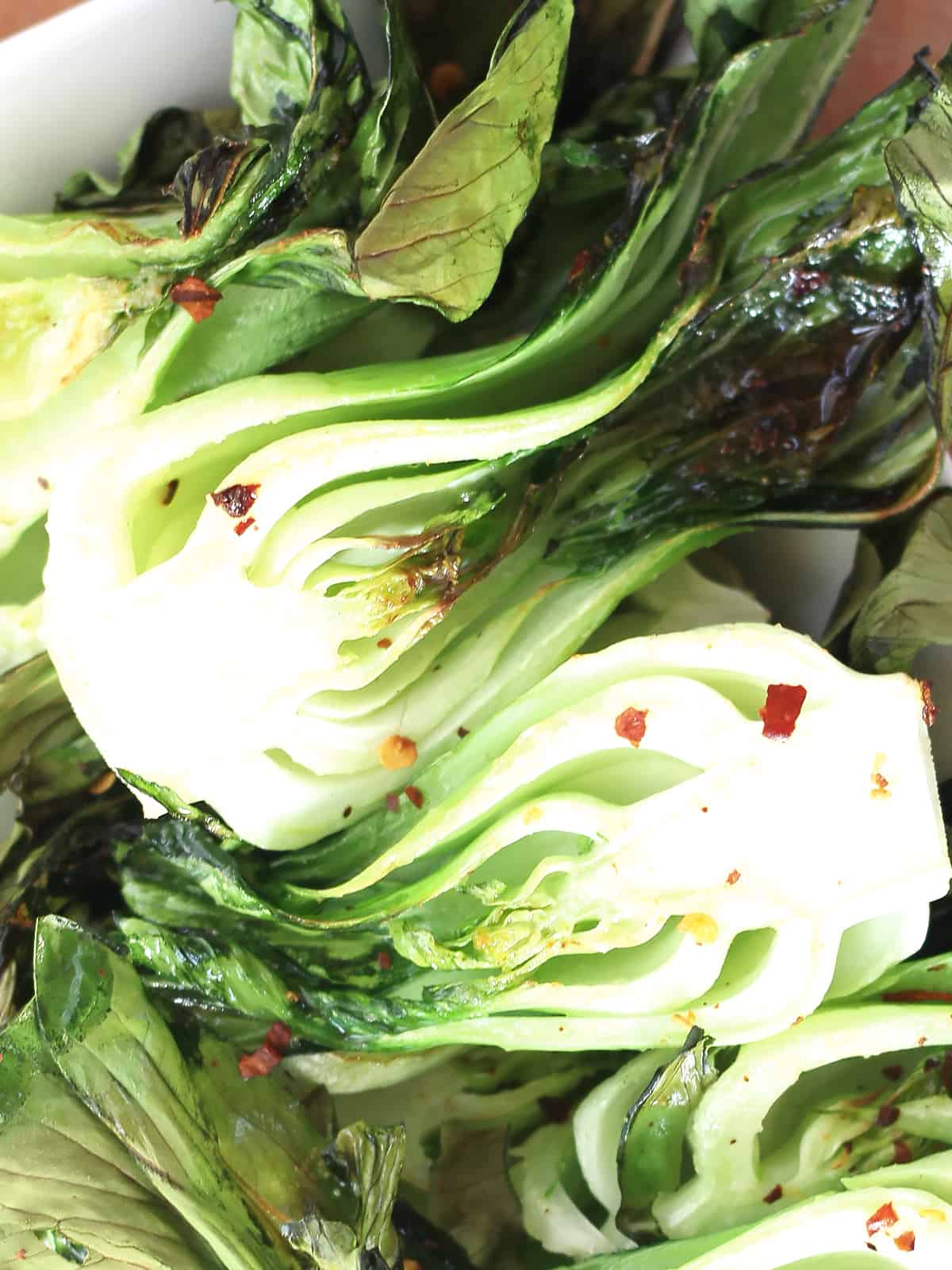 Halves of cooked pak choi sprinkled with chili flakes.