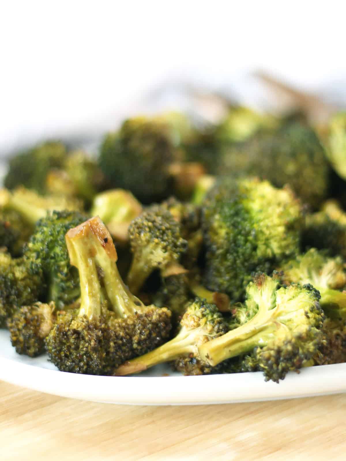 Close up of roasted broccoli florets on a serving plate.