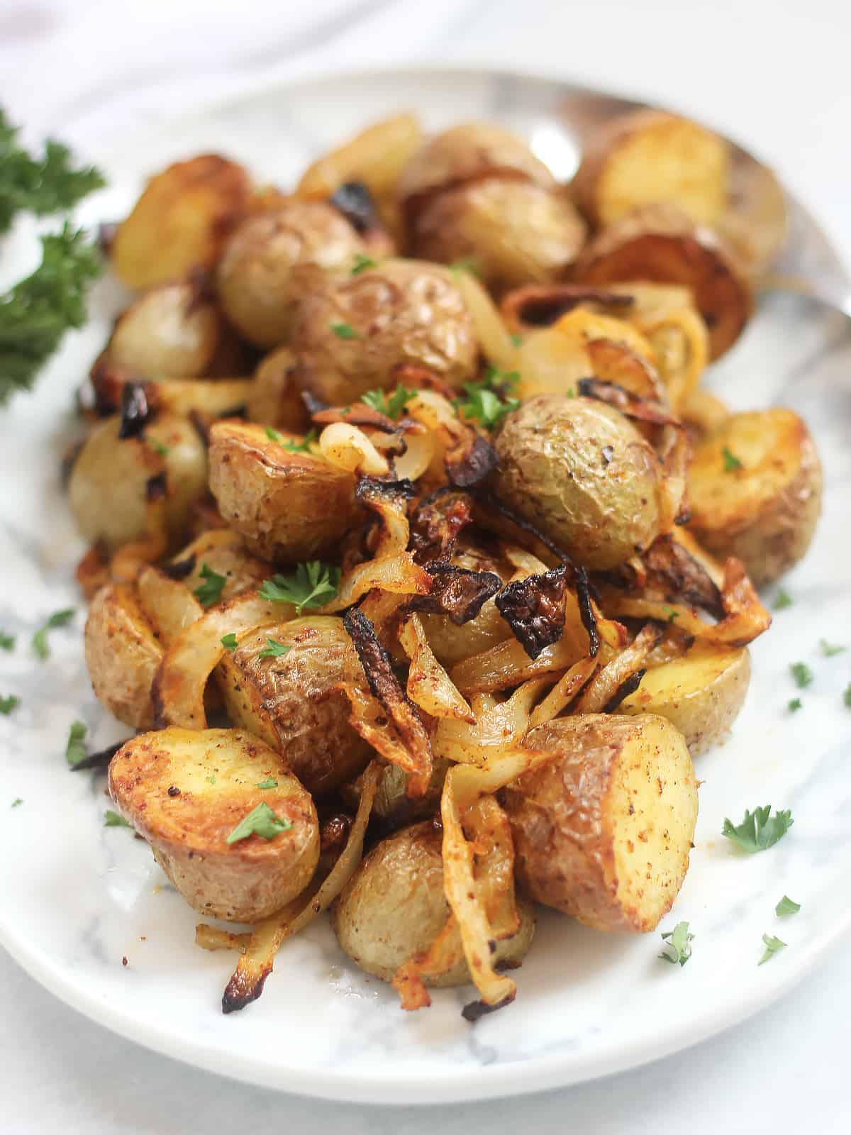 Roasted potatoes and sliced onions served on a white plate.