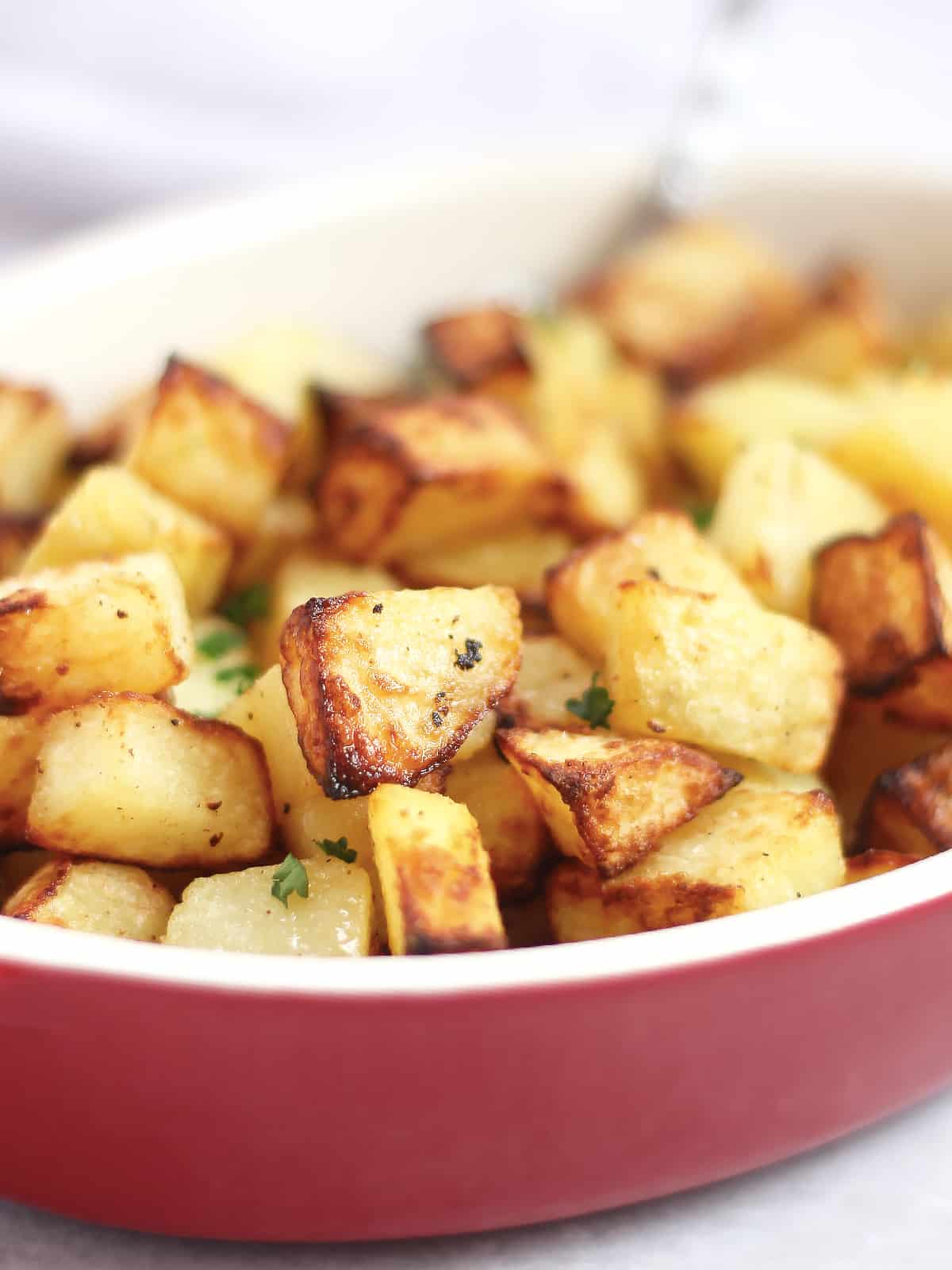 Diced potatoes with crispy edges in a red serving dish.