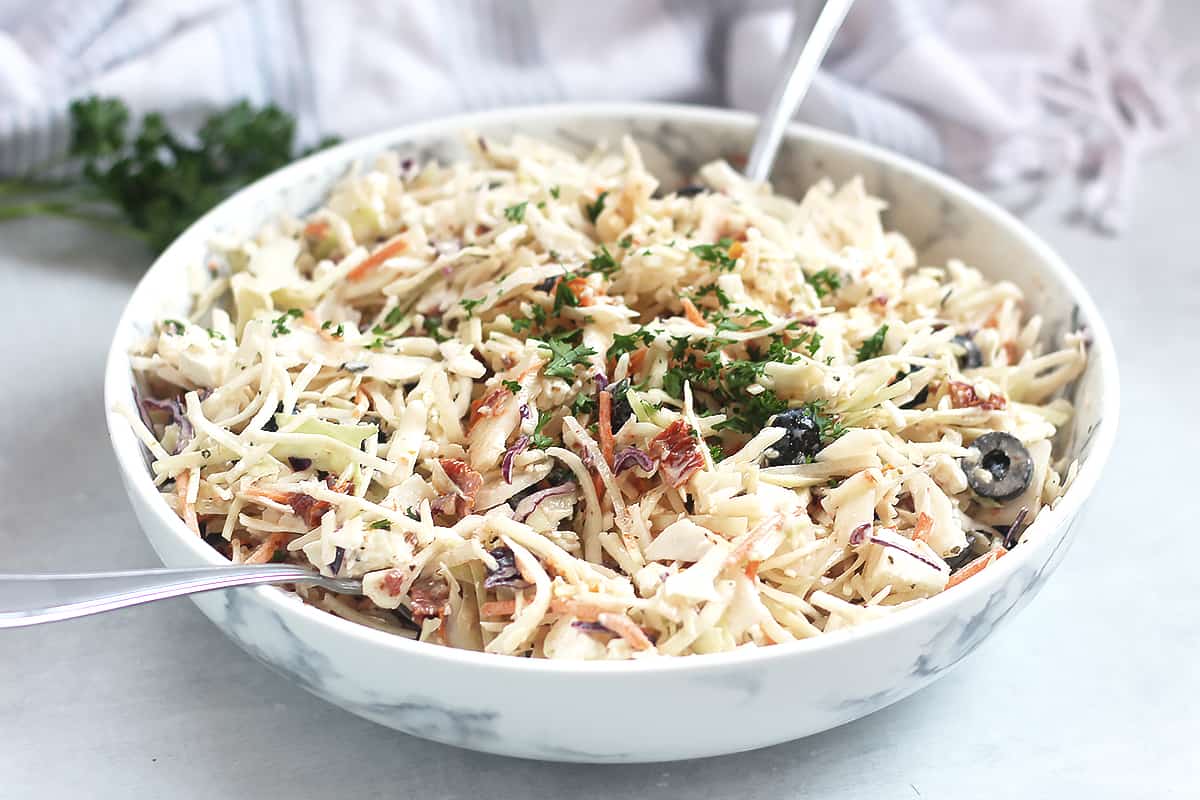 Mediterranean style slaw with creamy dressing in a serving bowl.
