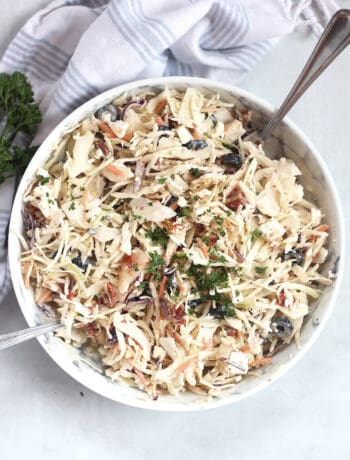 Mediterranean coleslaw served in a bowl with two serving spoons.