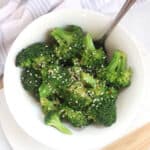 Asian style broccoli served in a white bowl with a spoon.