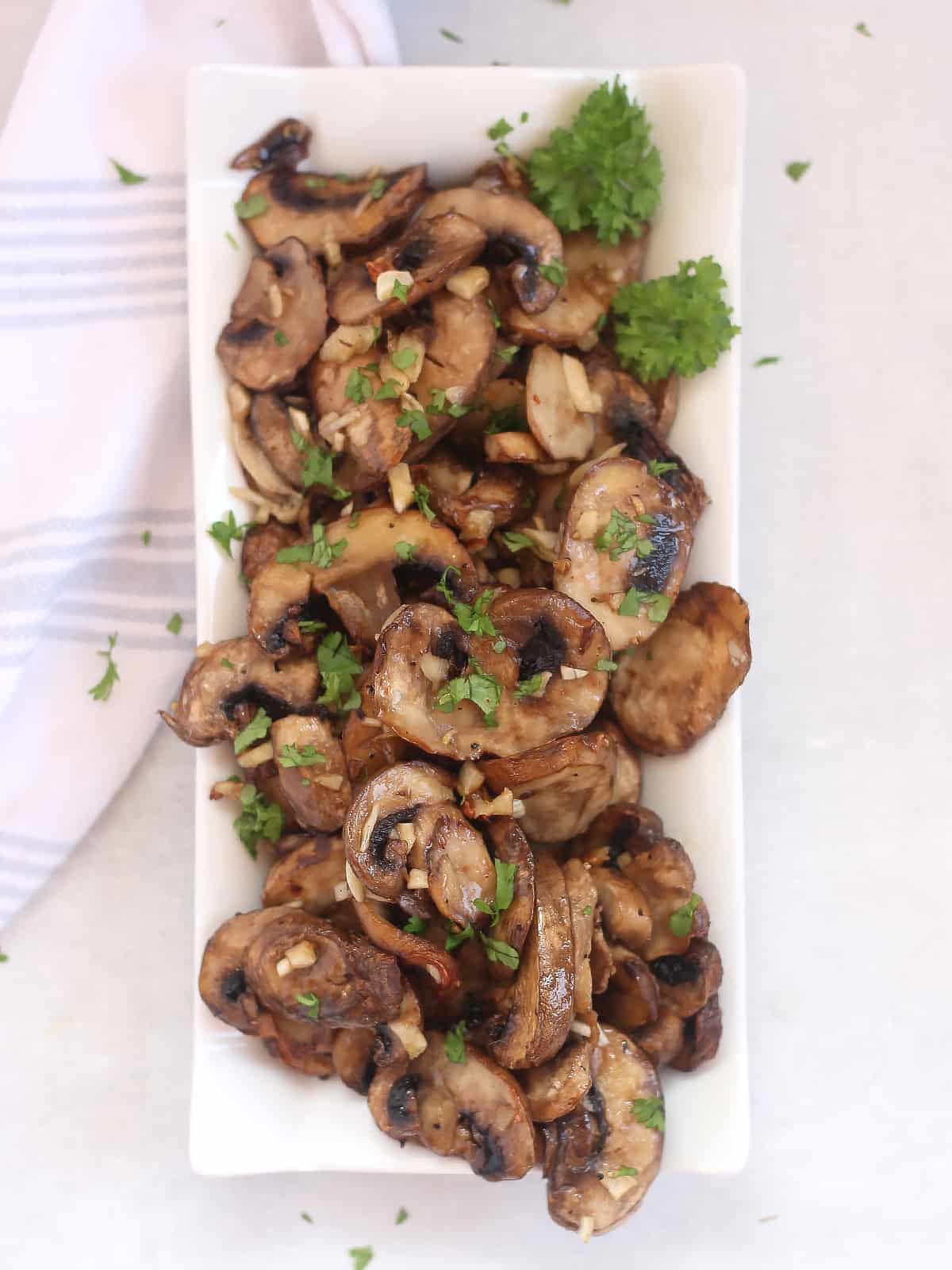 Air fried garlic mushrooms served on a plate with fresh parsley.