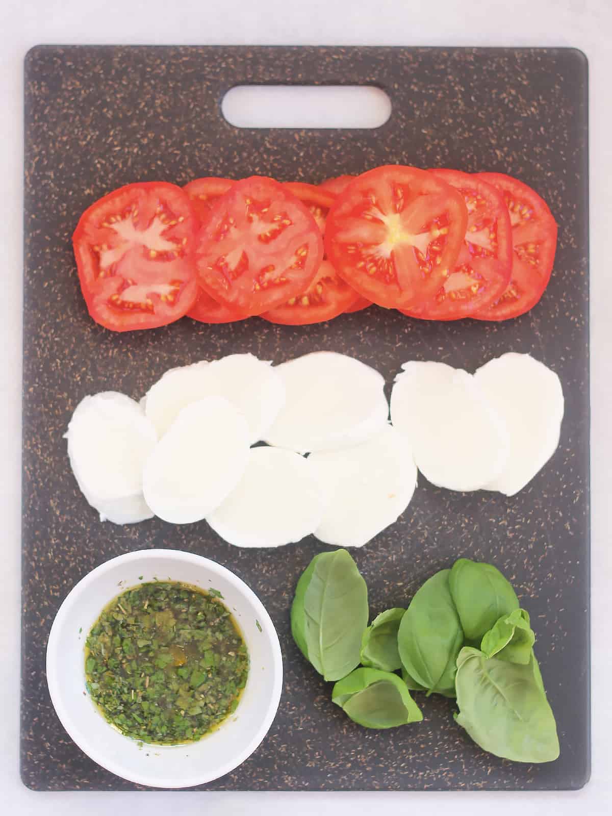 Ingredients to make caprese salad stacks on a chopping board.