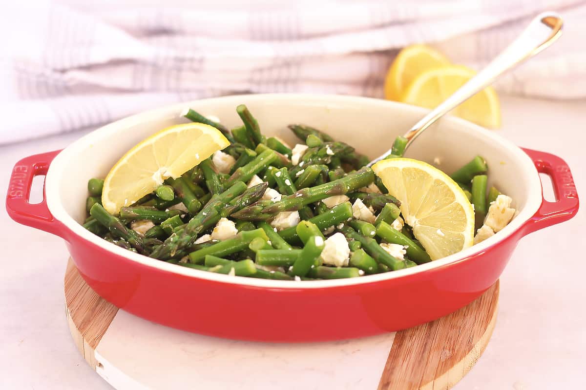 Cold asparagus salad served in a red dish.