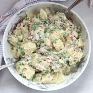 Potato salad with green peas in a serving bowl.