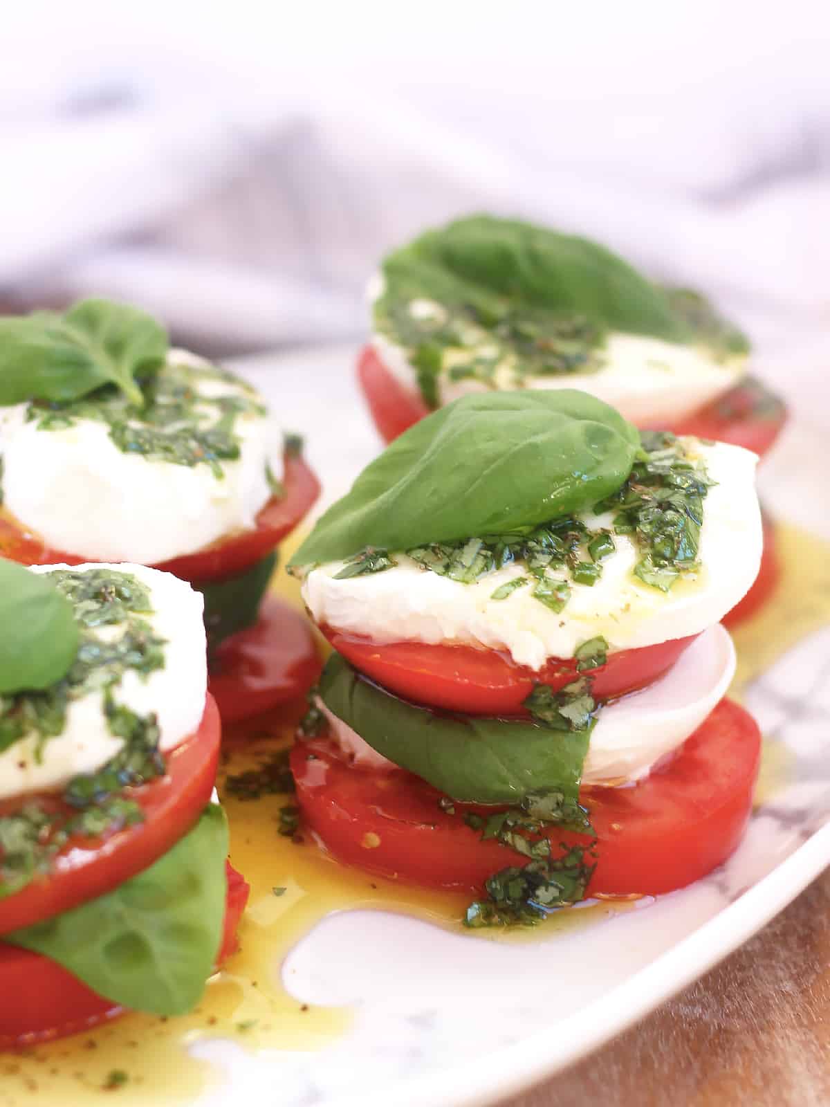 Caprese salad stacks drizzled with basil olive oil.
