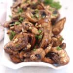 Air fryer garlic mushrooms on a white serving plate.