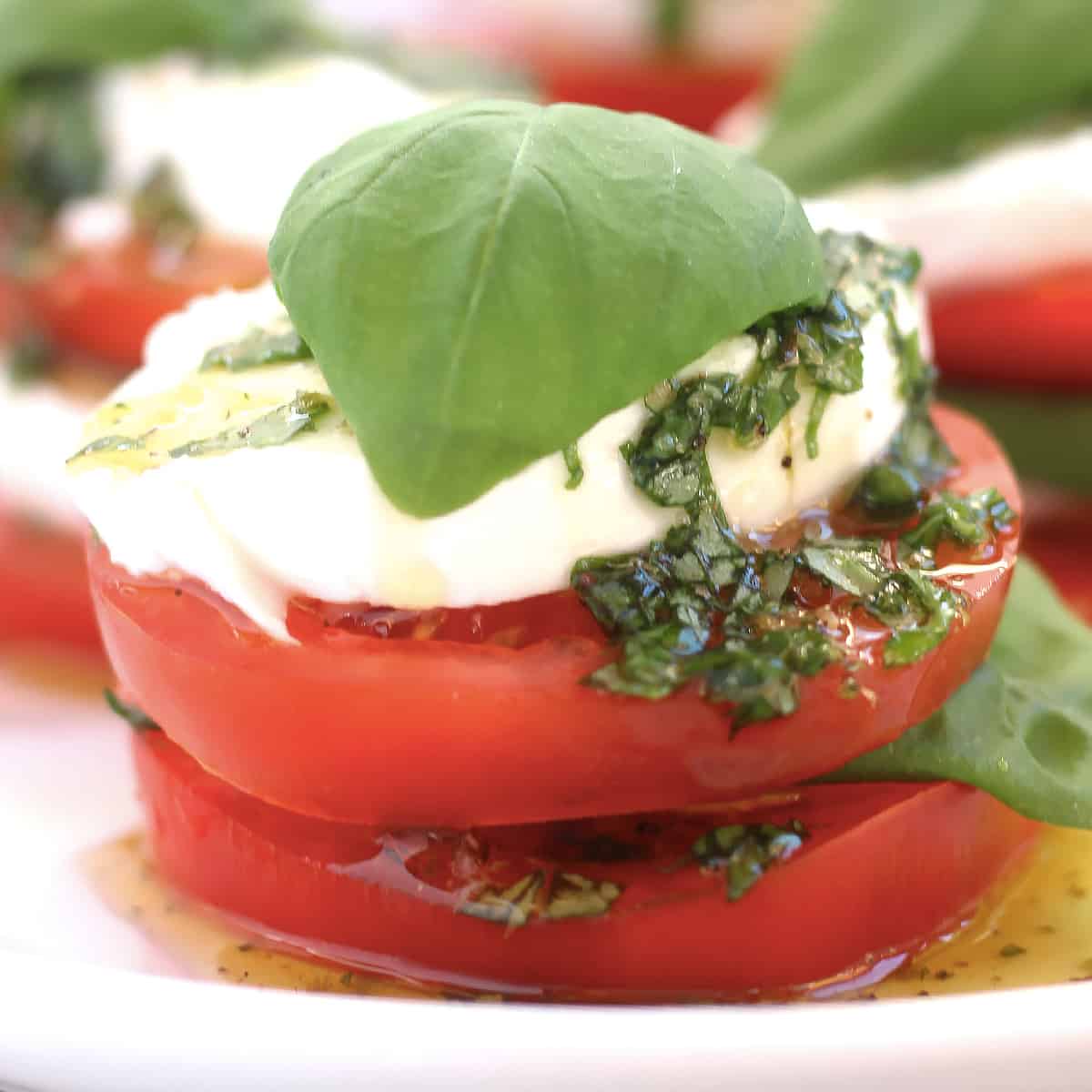 Slices of tomato, basil and mozzarella stacked on top of each other.