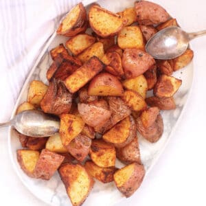 Air fryer roasted red potatoes on a serving plate with two spoons.