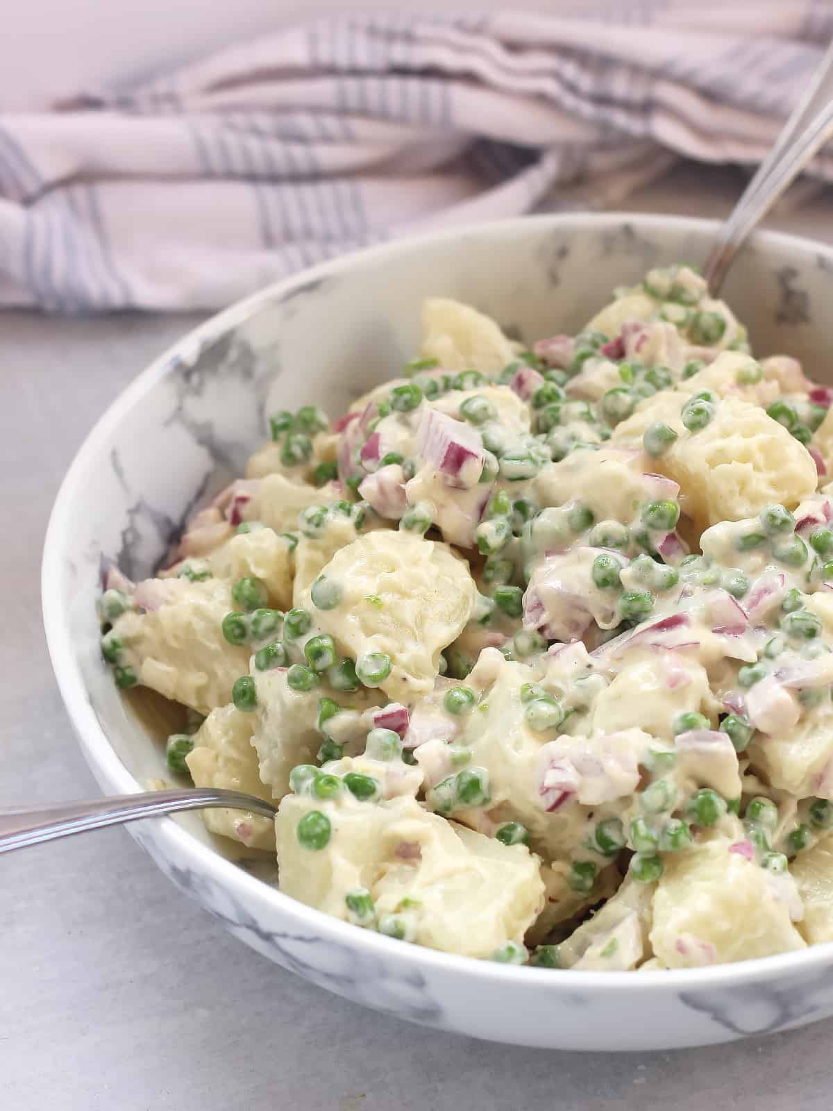 PEas mixed in with a creamy potato salad.