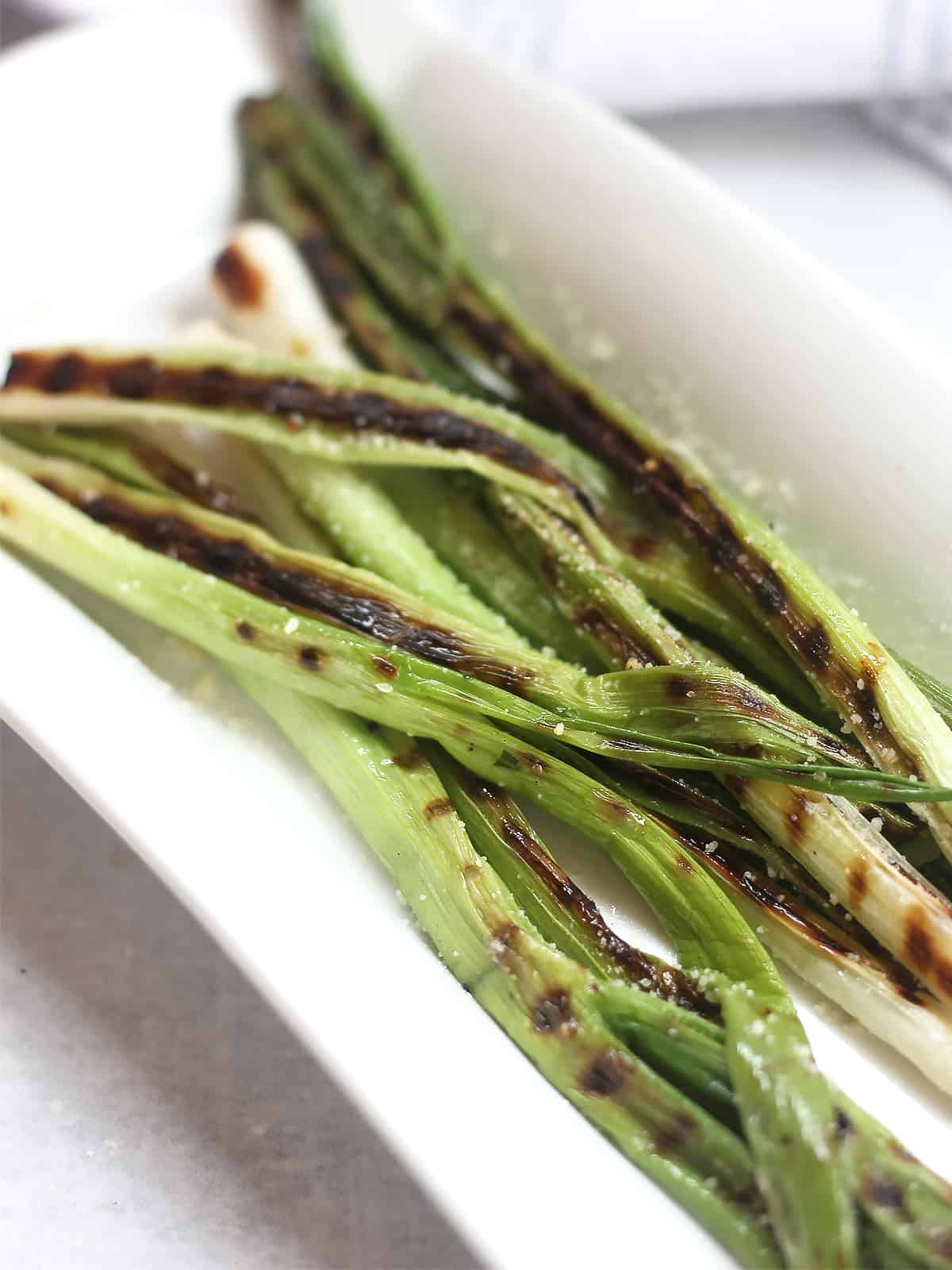 Grilled scallions garnished with parmesan cheese.