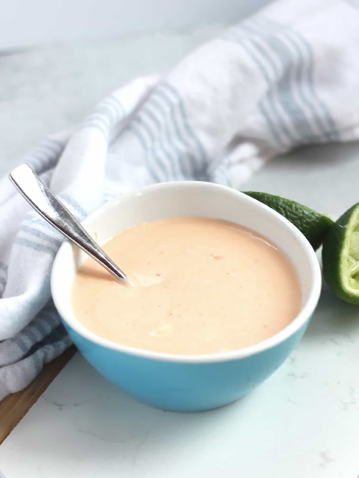 Creamy Thai dipping sauce in a blue bowl next to a fresh lime.