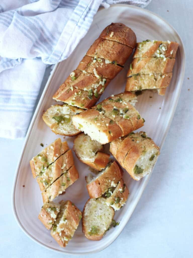 A broken garlic jalapeno baguette on a serving plate.