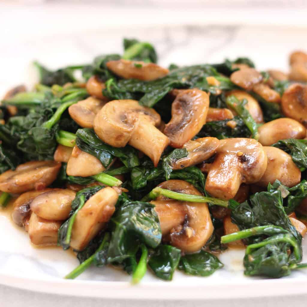 Sautéed mushrooms and spinach on a white plate.