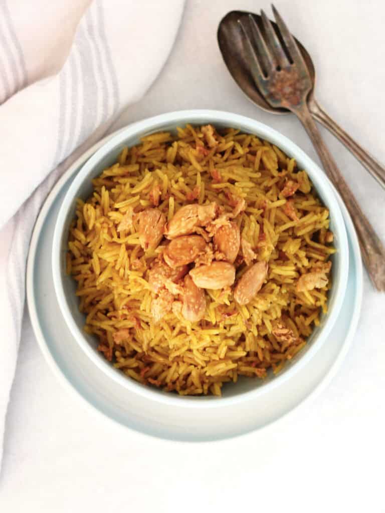 Egyptian rice served in a small blue bowl next to a fork and spoon.