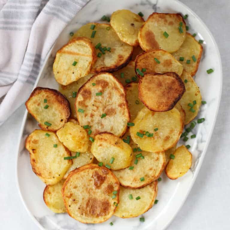 Air fried sliced potatoes garnished with fresh chives.