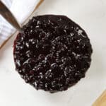 A spoon in a pot of blueberry sauce.