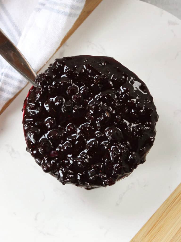 A spoon in a pot of blueberry sauce.