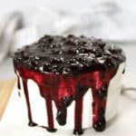 Blueberry sauce overflowing in a white ramekin.