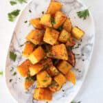 Butternut squash side dish served on a white plate with parsley garnish.