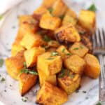 Butternut squash cubes on a plate garnished with parsley.