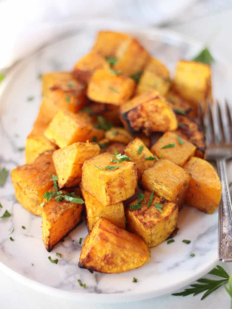 Butternut squash cubes on a plate garnished with parsley.