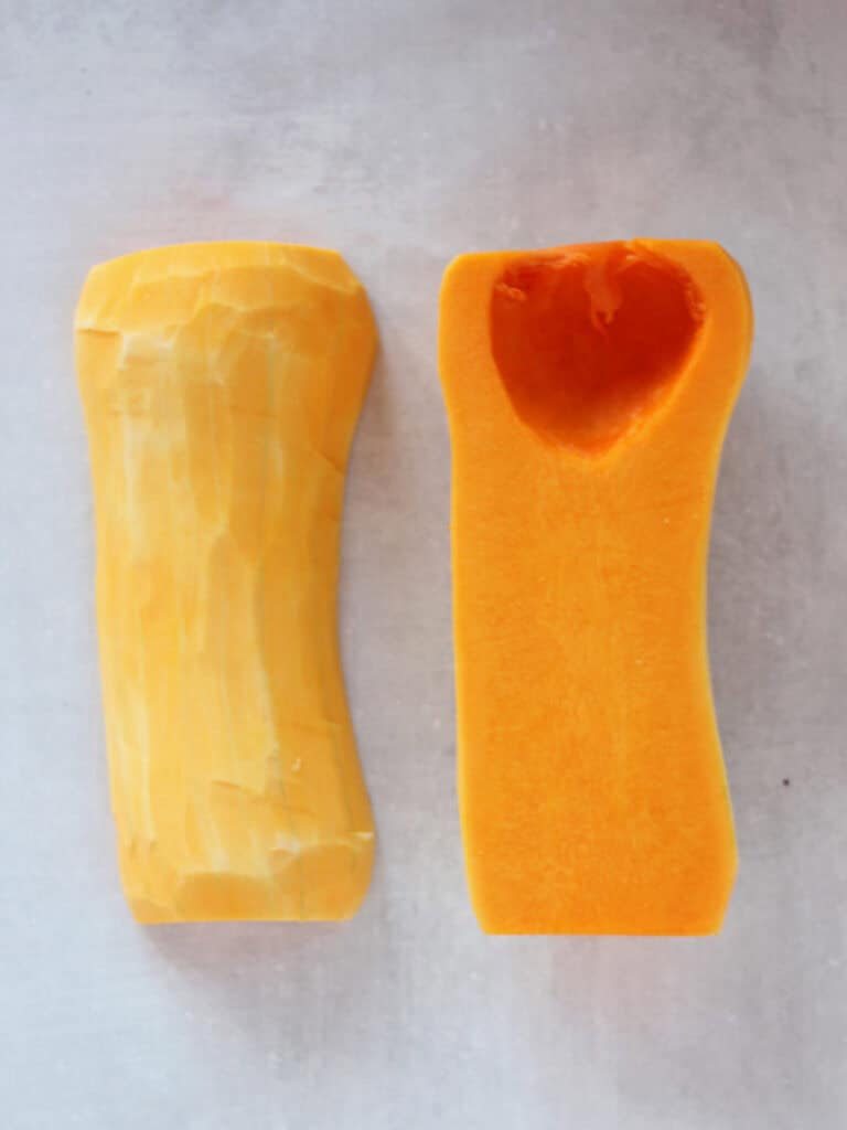 A butternut squash cut in half with the seeds scooped out.