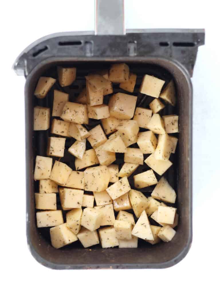 Uncooked rutabaga cubes in an air fryer basket.