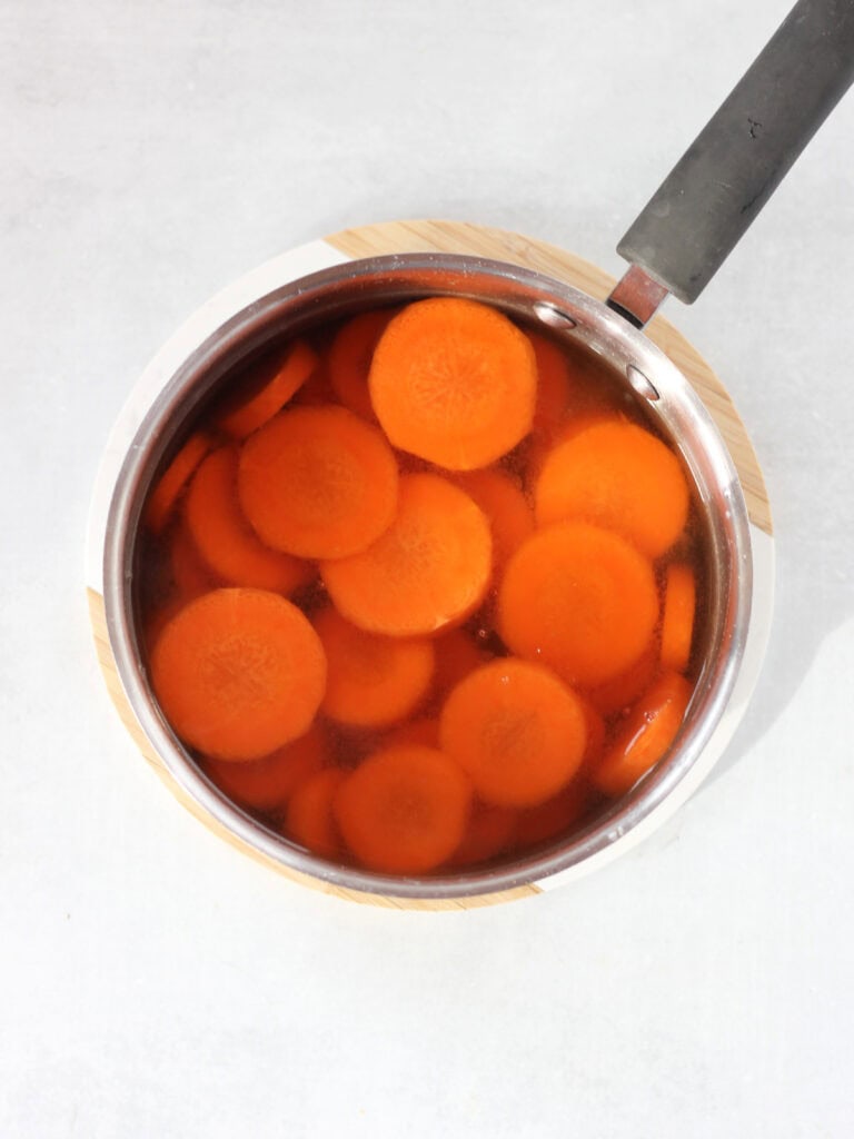 A pot with sliced carrots and stock.