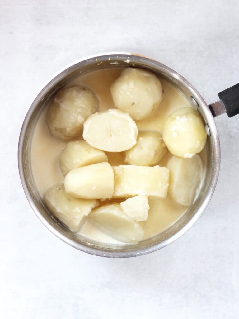 Cooked potatoes added to cream in a pot.