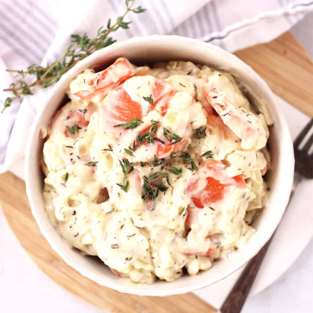 Creamed carrots served in a bowl with fresh thyme garnish.