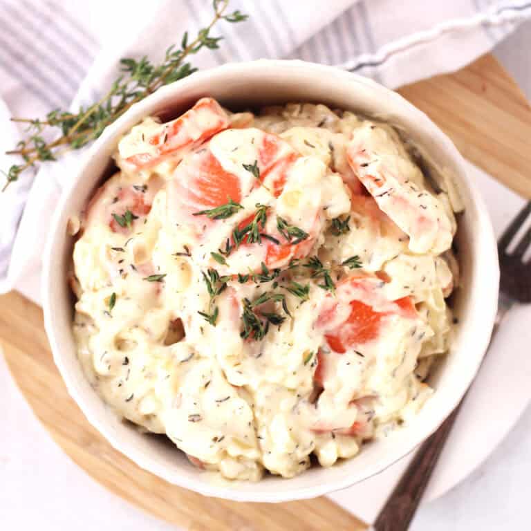 Creamed carrots served in a bowl with fresh thyme garnish.