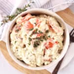 A bowl of creamed carrots next to a sprig of thyme.