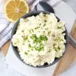 Mashed potatoes in a bowl next to a cut lemon.