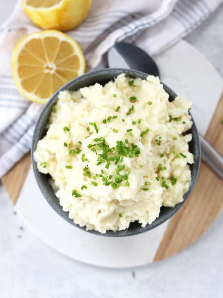 Mashed potatoes in a bowl next to a cut lemon.