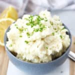 Mashed potatoes in a blue bowl garnished with chives.