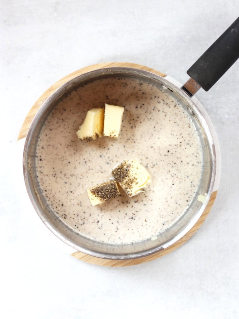 Milk, butter and black pepper in a silver pot.