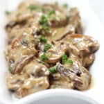 Cream covered mushrooms garnished with fresh herbs.