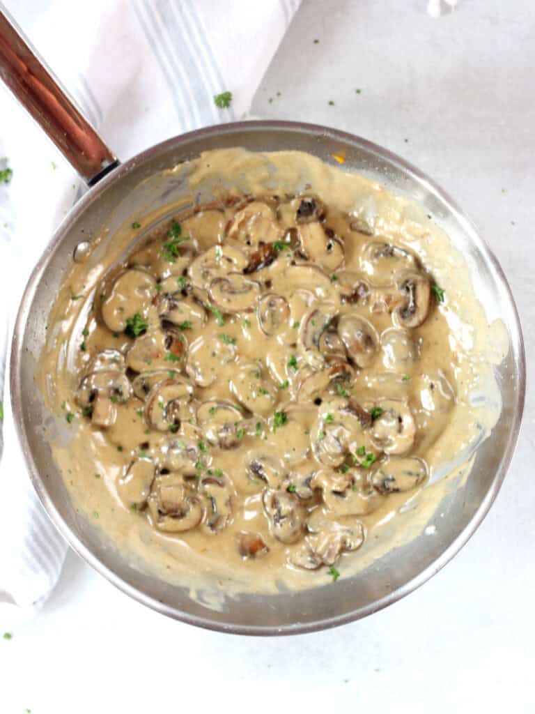 Creamy blue cheese mushrooms in a skillet garnished with parsley.